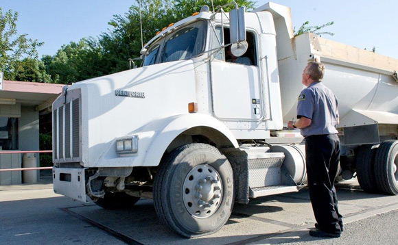 CIS Security guard at checkpoint for industrial plant, with large truck.